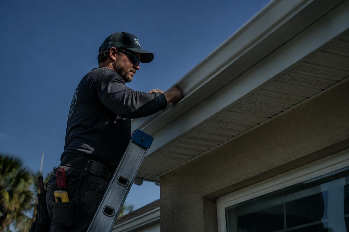 Technician installing a seamless gutter on a Florida home